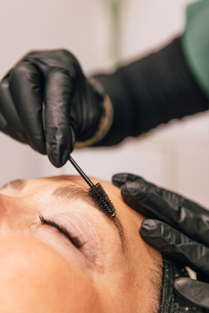 Close-up of the brow lamination process showing the aesthetician to carefully applying the lifting solution to create fuller, more defined natural brows.