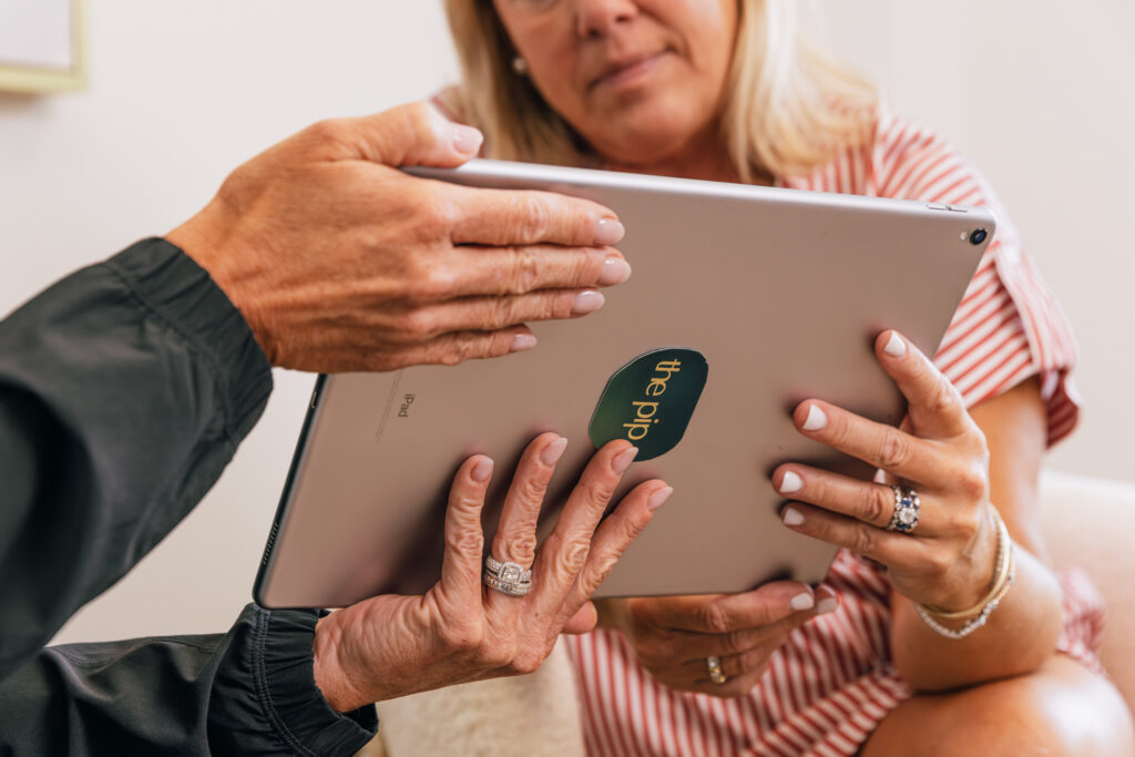 A patient reviews the plan for a chemical peel near Lenexa with her provider at The Pip Rx. They review potential depths of the peel together on a tablet-like device.